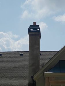 a chimney on the roof of a house with a blue sky in the background .